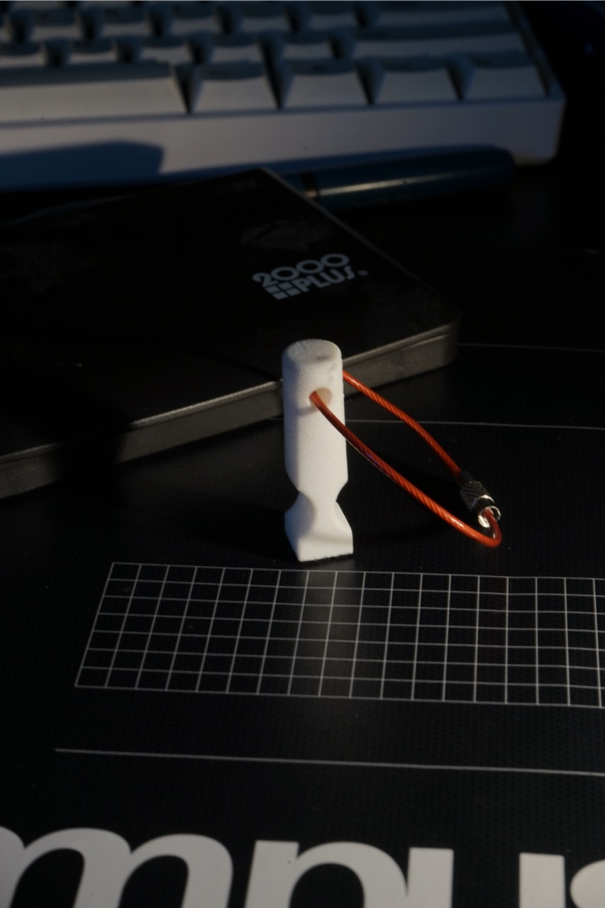 SLS printed stamp standing upright with a red keychain cable